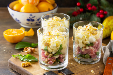 Fototapeta na wymiar Salad with Pear, Egg, Ham, Walnuts, Fruits and Arugula on the Festive Christmas Table.
