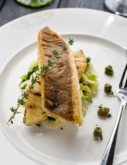 Fillet of halibut on a pillow of stewed leeks on the white plate.