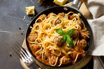 Spaghetti with Meatballs with Tomato Sauce and Parmesan Cheese on a dark stone or concrete background.