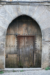 Fototapeta na wymiar Ancient dark wood entrance door of a stone house