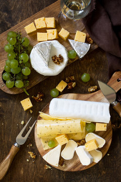Cheese plate. Assortment of cheeses, grapes and nuts on dark rustic wooden table. Top view flat lay background.
