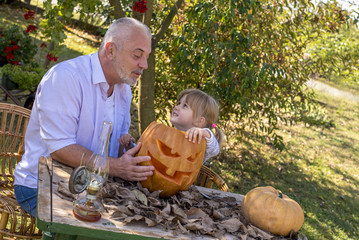 Grandchild having fun with grandfather while carving pumpkins together