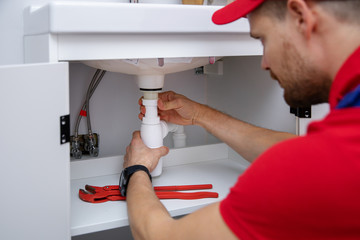 plumber installing sink siphon in domestic bathroom