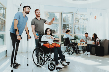 Man with Woman in Wheelchair and Man on Crutches.
