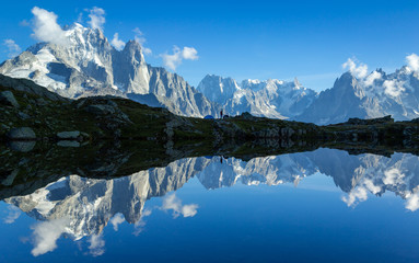 Hiker at his tent in the Mont Blanc massif reflected in Lac de Chesery. Chamonix, France.