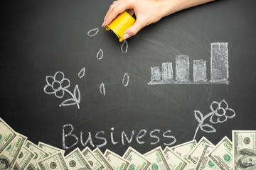 Watering and business word in a concept board for business growth, investment, savings and making money, a lot of dollars