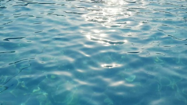  Beautiful background from blue waters rippling, calming and sparkling with a golden sun path in an outdoor swimming pool in slow motion