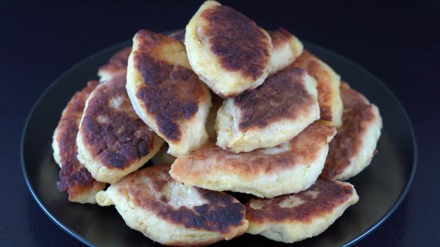 Potato cakes, ukrainian name potato zrazy, stuffed mushrooms or meat or cheese with herbs cream are fried in vegetable oil on black background, close up, rotates. Traditional Ukrainian cuisine