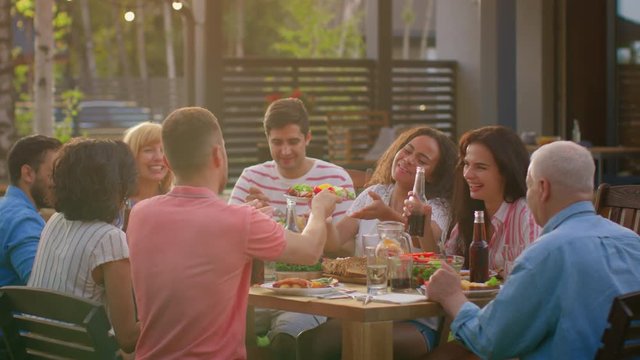 Big Family Garden Party Celebration, Gathered Together at the Table Relatives and Friends, Young and Elderly are Eating, Drinking, Passing Dishes, Joking and Having Fun. 