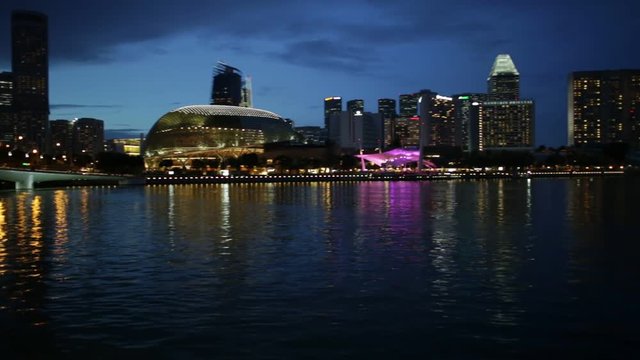 Skyline of Singapore with cruise sails in the harbor at blue hour. Tourist boat on foreground. Night scene waterfront in marina bay area.