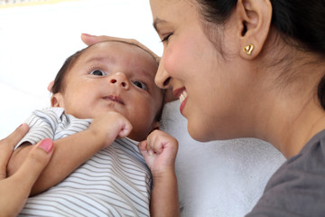 Cheerful mother playing with newborn baby