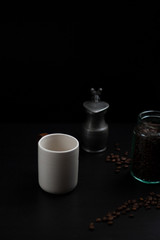 a cup of coffee and coffee beans on dark table