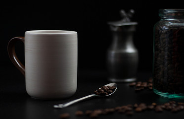 cup of coffee and jar of coffee beans on dark table