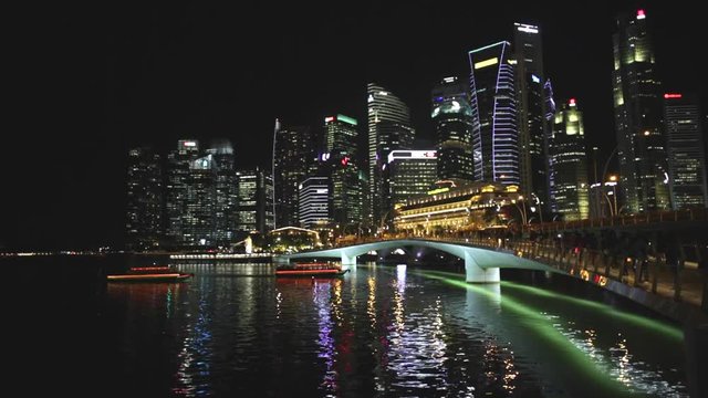 Singapore financial buildings and skyscrapers of downtown reflected in the sea of the harbor with ferry boats. Singapore skyline night scene in marina bay waterfront.