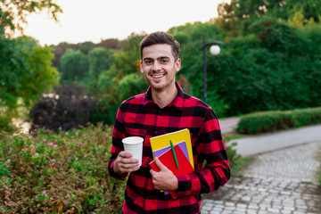 Happy student  drinking hot coffee and resting after studying. Handsome and stylish brunet male...