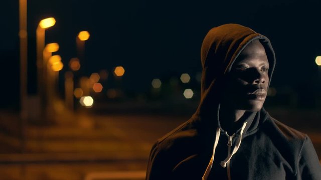 pride, race, belonging. A young Afro-hooded boy stares at the camera at night