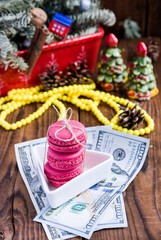 Pink macaroons and twenty euros with christmas decorations on woooden