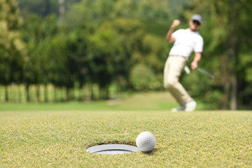Golfeur homme acclamant après une balle de golf sur un green de golf