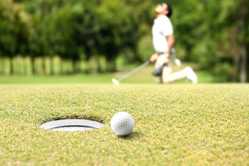 Man golfer cheering after a golf ball on a golf green