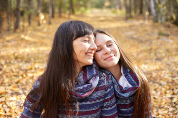 Cute portrait of mother and daughter in the autumn forest.