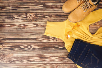 Flatlay of autumn clothes. Top view of woman`s clothes. Sweater, jeans and boots on wooden...