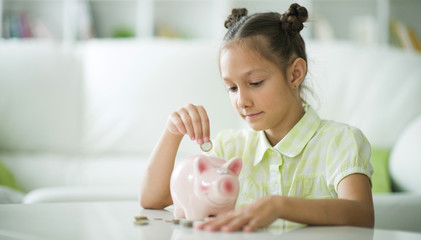 Portrait of a cute little girl with a piggy bank