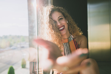 Content woman outstretching hand at camera in sunlight