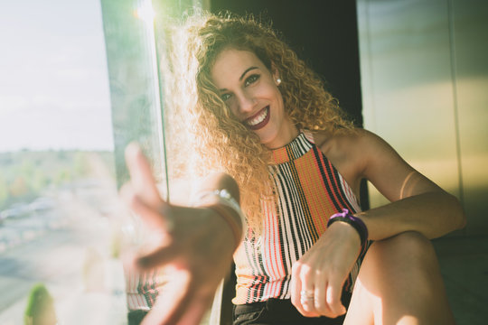 Content Woman Outstretching Hand At Camera In Sunlight