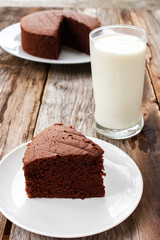 Sliced homemade chocolate cake on white served with milk. Food and drink background.