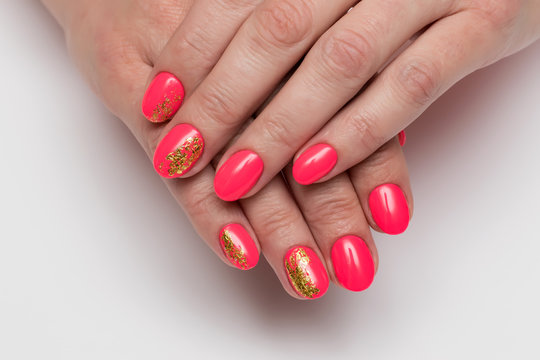 Summer Red, coral manicure with gold foil on short oval nails on a white background close-up
