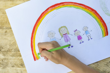 Children's hands paint a drawing with a brush and paints. Top view