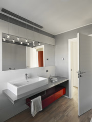 interiors shots of a modern bathroom in the foreground the counter top washbasin and the red furniture