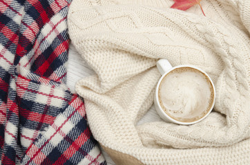Fototapeta na wymiar Cappuccino, milk knitted sweater, checkered plaid and autumn leaves. Fashionable concept