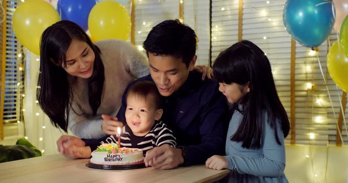 Little boy blows out candles on birthday cake at party with happy emotion. People with party and celebration concept. 4K Resolution.
