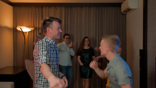 Two guys and their friends dancing at home party. Happiness, fun and crazy moving by sound music beat. 4k UHD. Slow motion