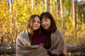 Cute portrait of mother and daughter in the autumn forest.