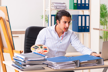 Young handsome employee enjoying painting at the office 