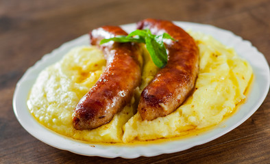 fried meat sausages with mashed potatoes in white plate on wooden table background