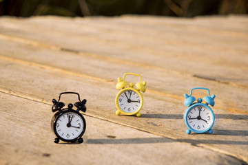 Three small alarm retro clocks on wooden surface. Autumn abstract photo.