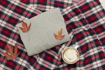 Gray sweater, plaid and coffee mug. Autumn leaves. Fashionable concept