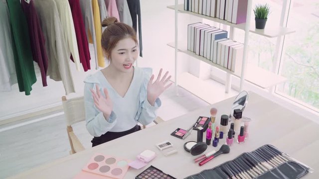 Beauty blogger present beauty cosmetics sitting in front camera for recording video. Beautiful asian woman use cosmetics while review make up tutorial broadcast live video to social network.