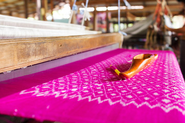 Silk loom on pink silk. Traditional weaving of Thai silk. Cloth background.