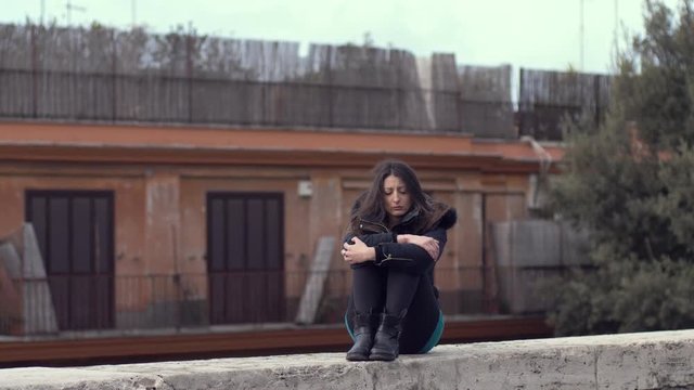 loneliness, depression, problems. Depressed sad youn woman alone sitting on wall