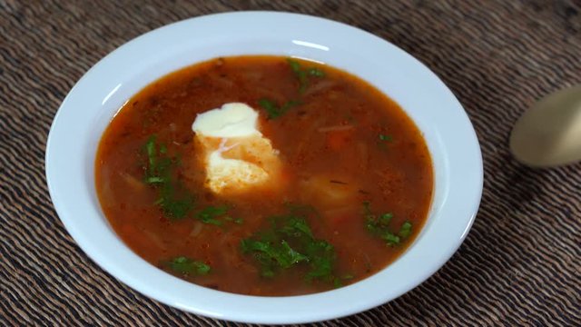 White plate with a homemade appetizing and tasty borsch. Red beetroot vegetable soup. Ukrainian and russian traditional red beet soup - borscht or borsch, close up