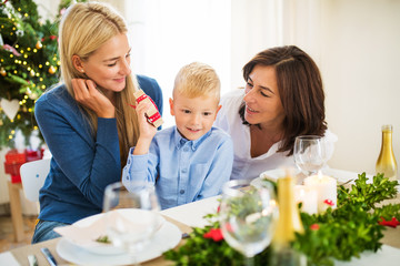A small boy with present and mother and grandmother at home at Christmas time.