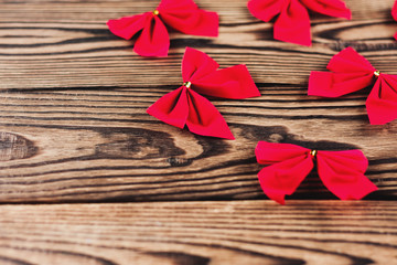 Lot of red christmas bows scattered on old wooden table. With copy space for your text