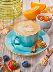 Cappuccino in a blue cup with biscuit cookies on a rustic wooden table