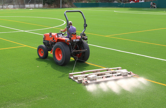 tractor preparando el nuevo c&eacute;sped artificial de un campo de f&uacute;tbol, poniendo arena