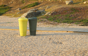 contenedores de plástico, bricks y latas y material orgánico, de color amarillo y verde en la arena de una playa de Galicia