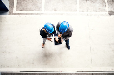 A top view of an industrial man and woman engineer with tablet in a factory, working.